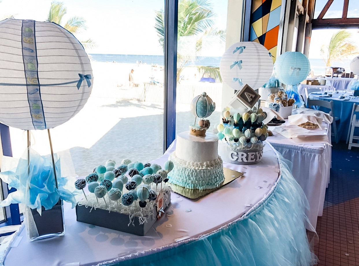 A dessert table featuring baby shower treats such as cakes, cake pops and lollies.