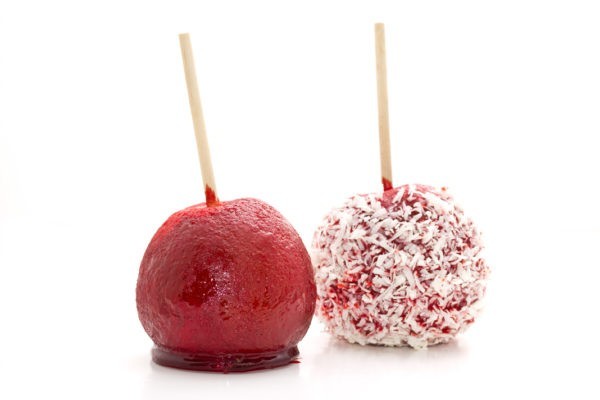 Two candy apples, one red and the other red covered in coconut flakes.