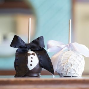 Two Groom and Bride chocolate covered apples dressed in a tux and dress with bows.