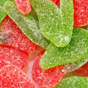 A close up of a bunch of sour cherry shaped gummies.