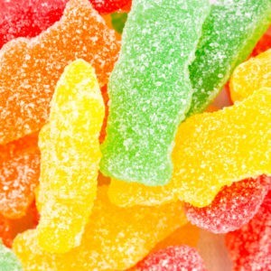 An assortment of Sour Patch Kid gummies in yellow, orange, red and green.