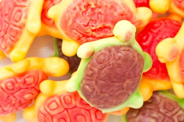 Close up of green gummy turtles with red shells.