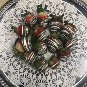 A bunch of chocolate covered strawberries with white chocolate drizzled on top.