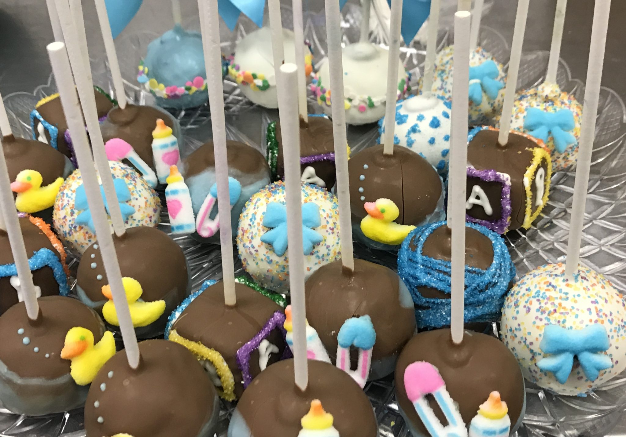 A tray of assorted baby shower cake pops.