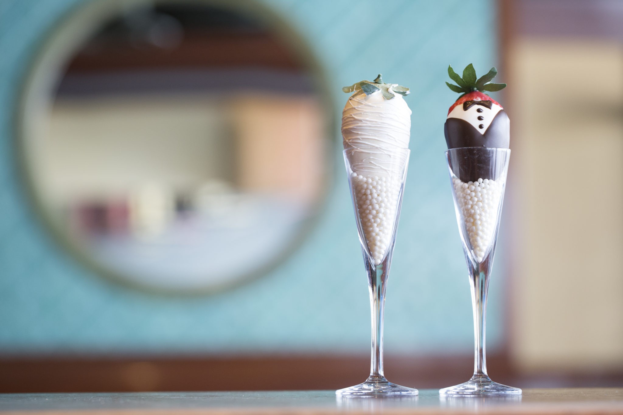 Bride and groom chocolate covered strawberries displayed in champagne flutes.