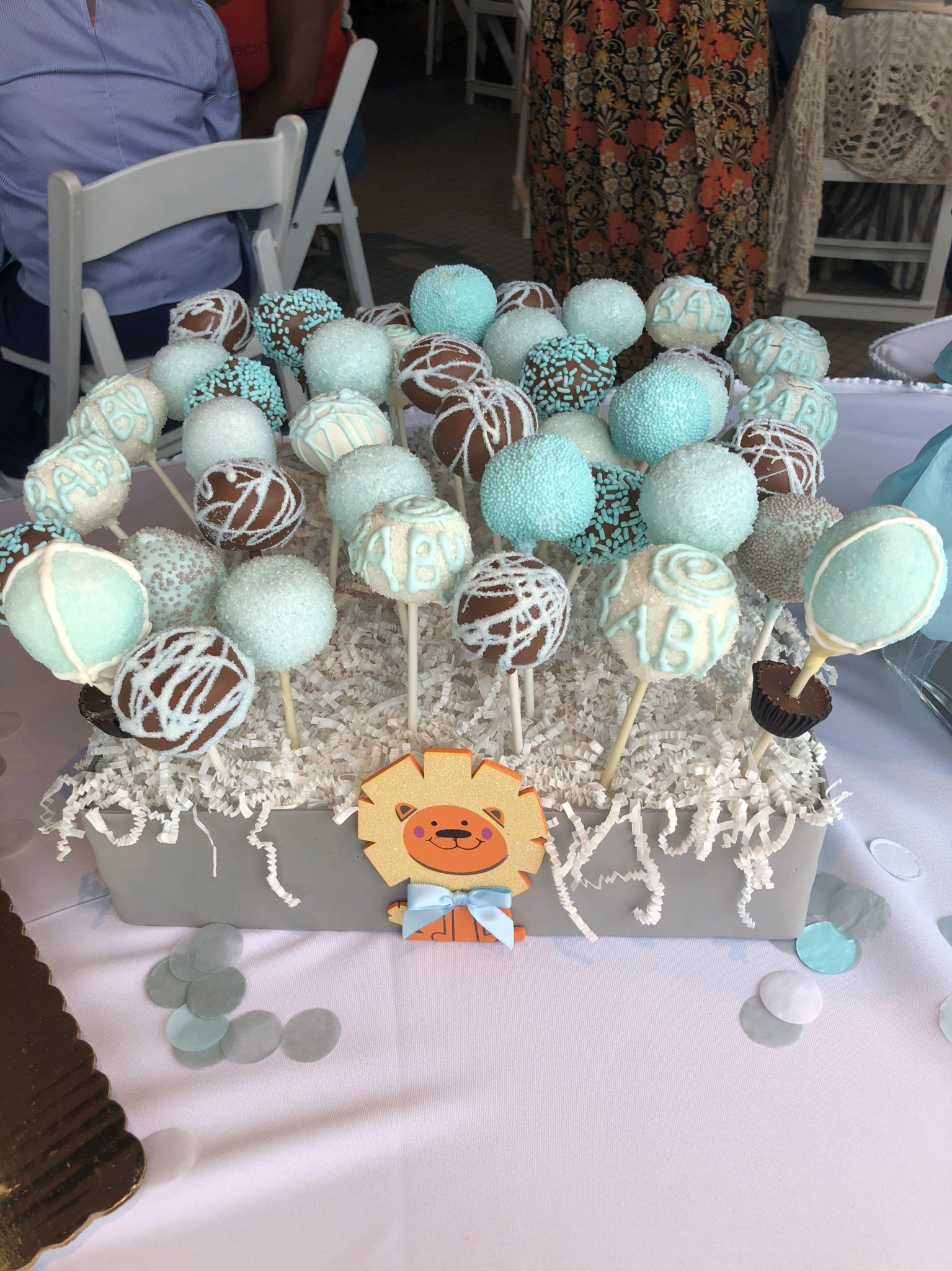 A custom display of assorted blue chocolate cake pops for a baby shower.