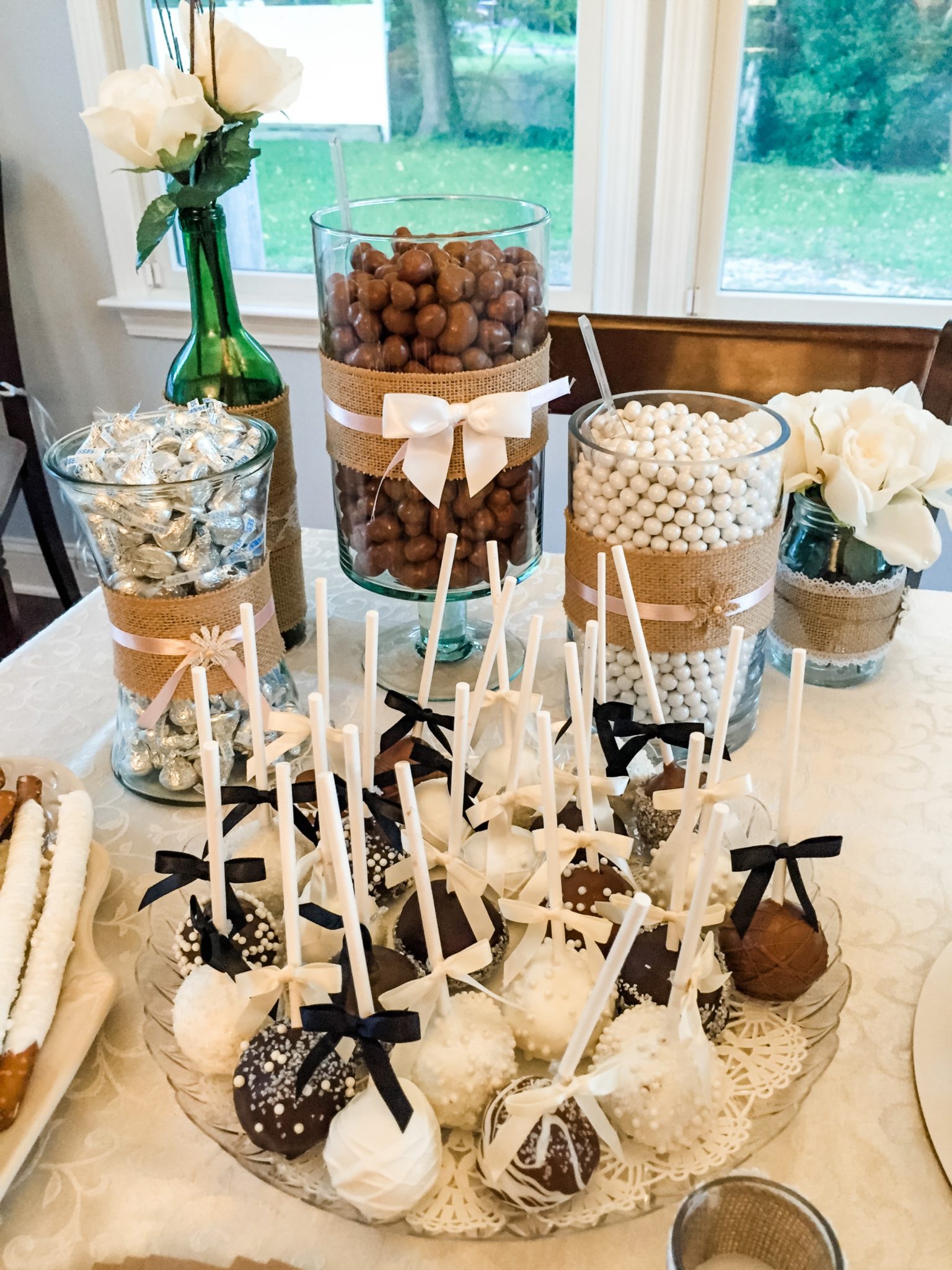 A custom dessert table at a bridal shower featuring assorted jars filled with candy and chocolate treats.