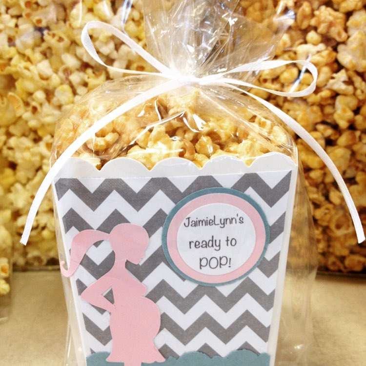 Caramel covered popcorn favors displayed in a "She's About to Pop" container.
