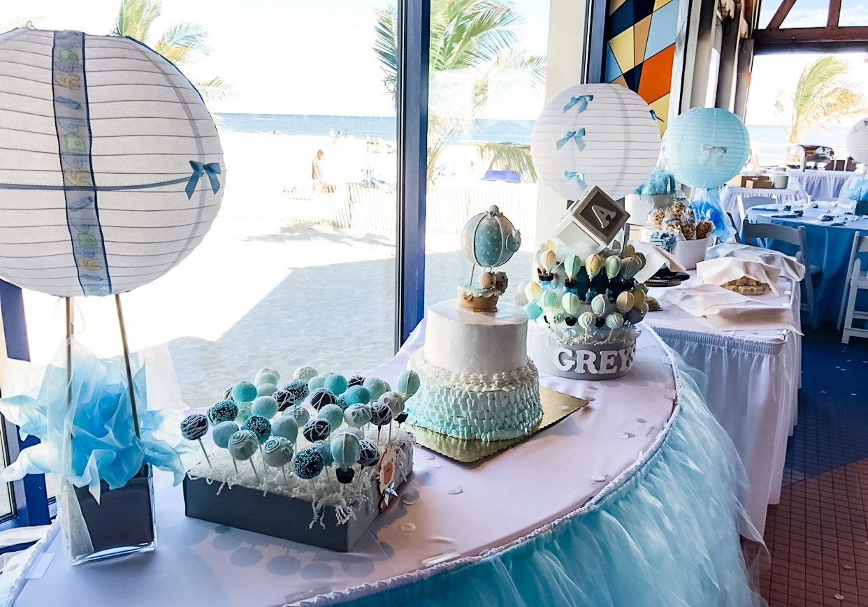 A dessert table featuring baby shower treats such as cakes, cake pops and lollies.
