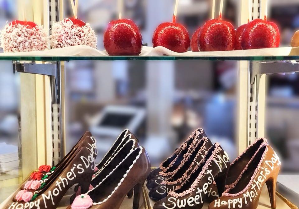 A display case in Jenkinson's Sweet Shop featuring Mother's Day inspired chocolate high heels and red candy apples.