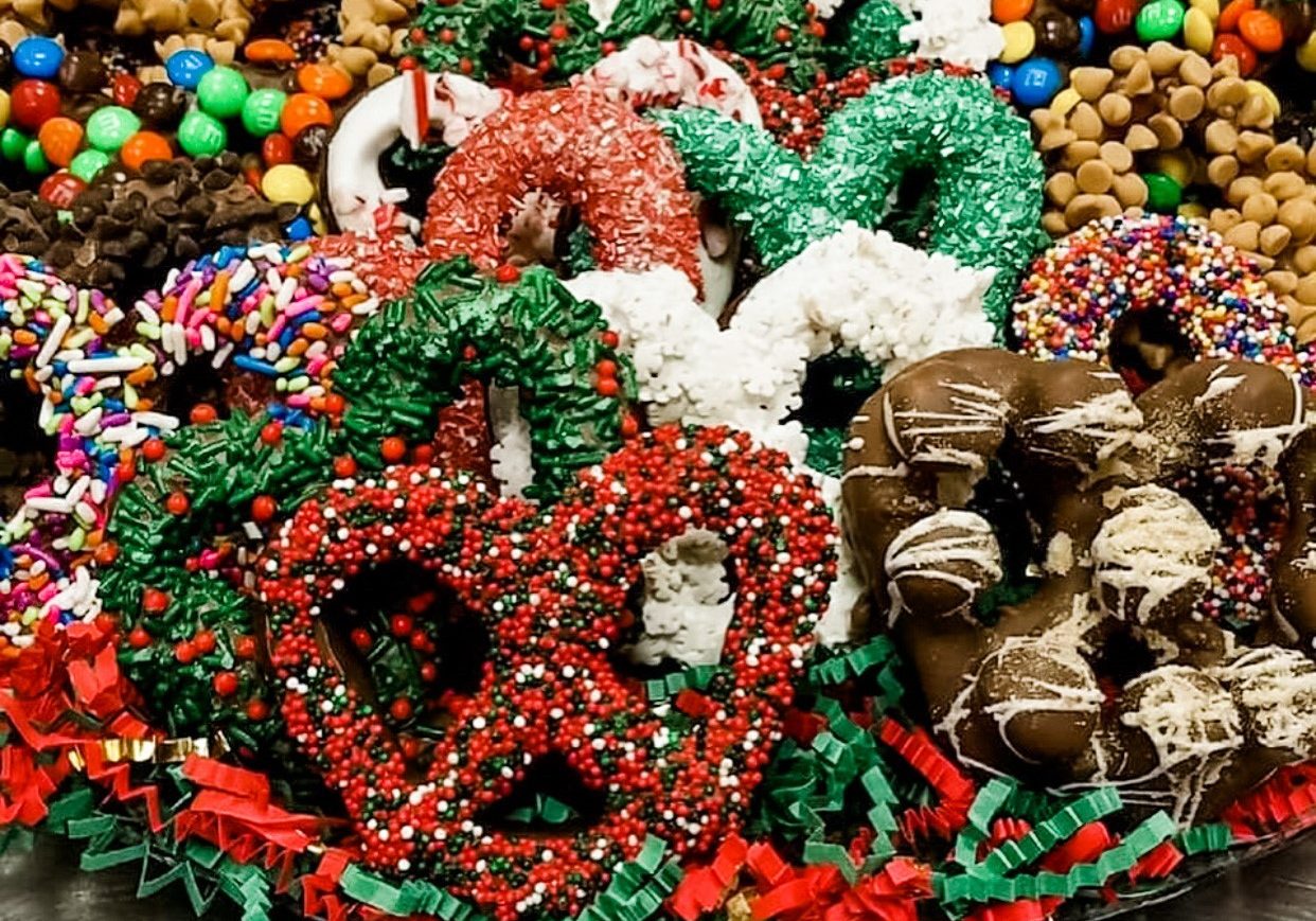 A large platter of assorted chocolate covered pretzels with an array of Christmas sprinkles and toppings.