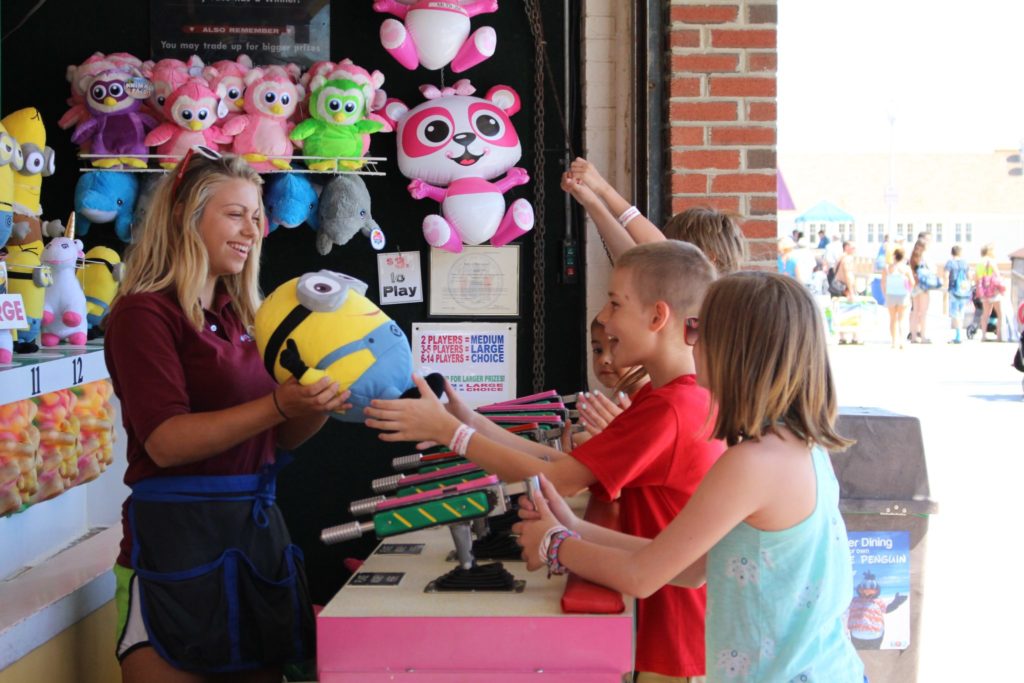 An employee at Jenkinson's Boardwalk giving the winning child of The Water Gun Game their prize.