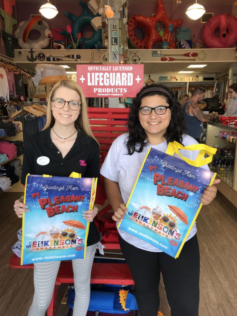 Two Jenkinson's Boardwalk Gift Shop employees holding up gift bags.