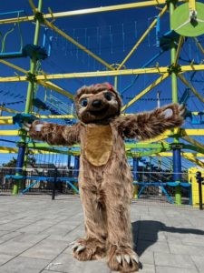 sloth mascot in front of climbing structure.
