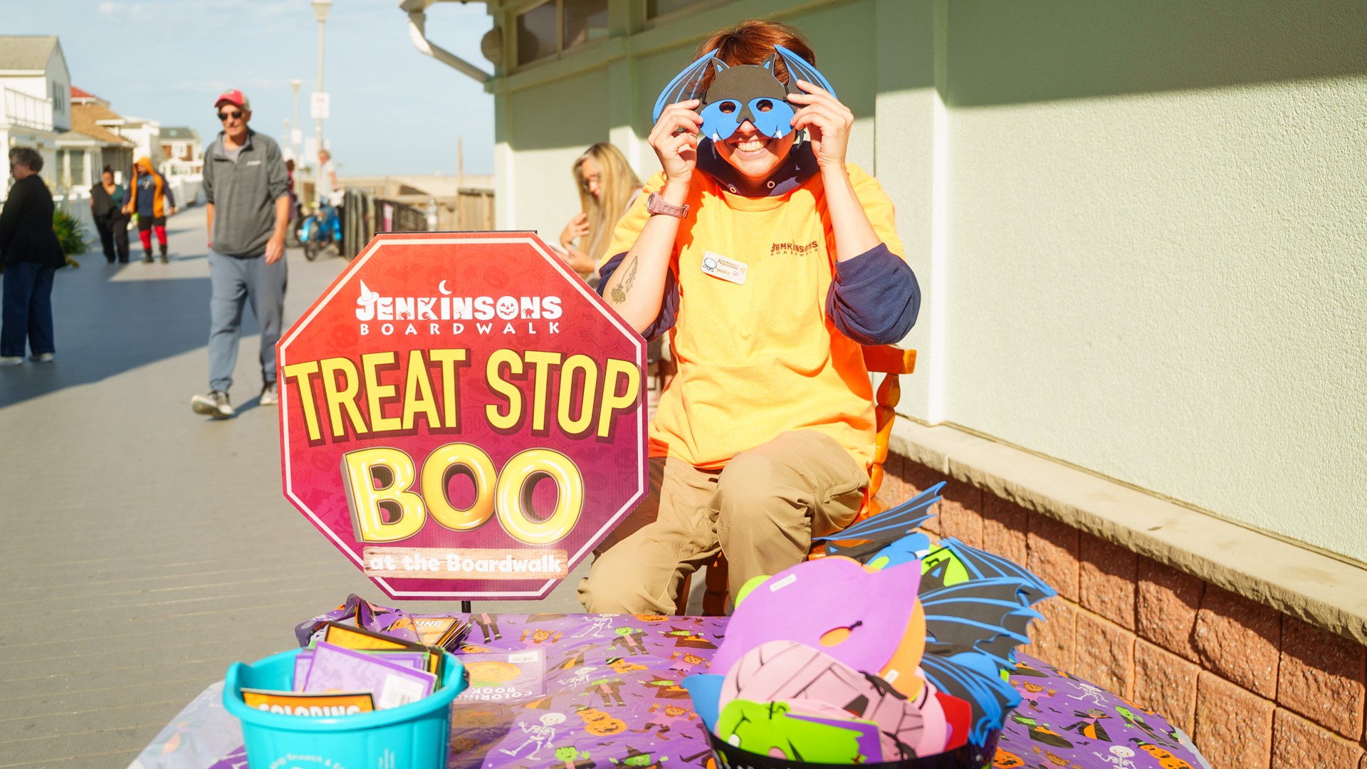 A Jenkinson’s Boardwalk team member holding up a bat mask at a Treat Stop station during Boo at the Boardwalk.