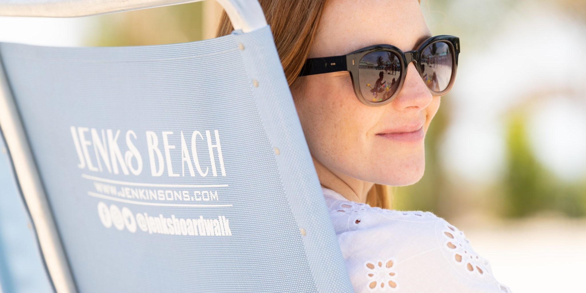 A woman sits in a beach chair with sunglasses on at the beach located at Jenkinson's Boardwalk