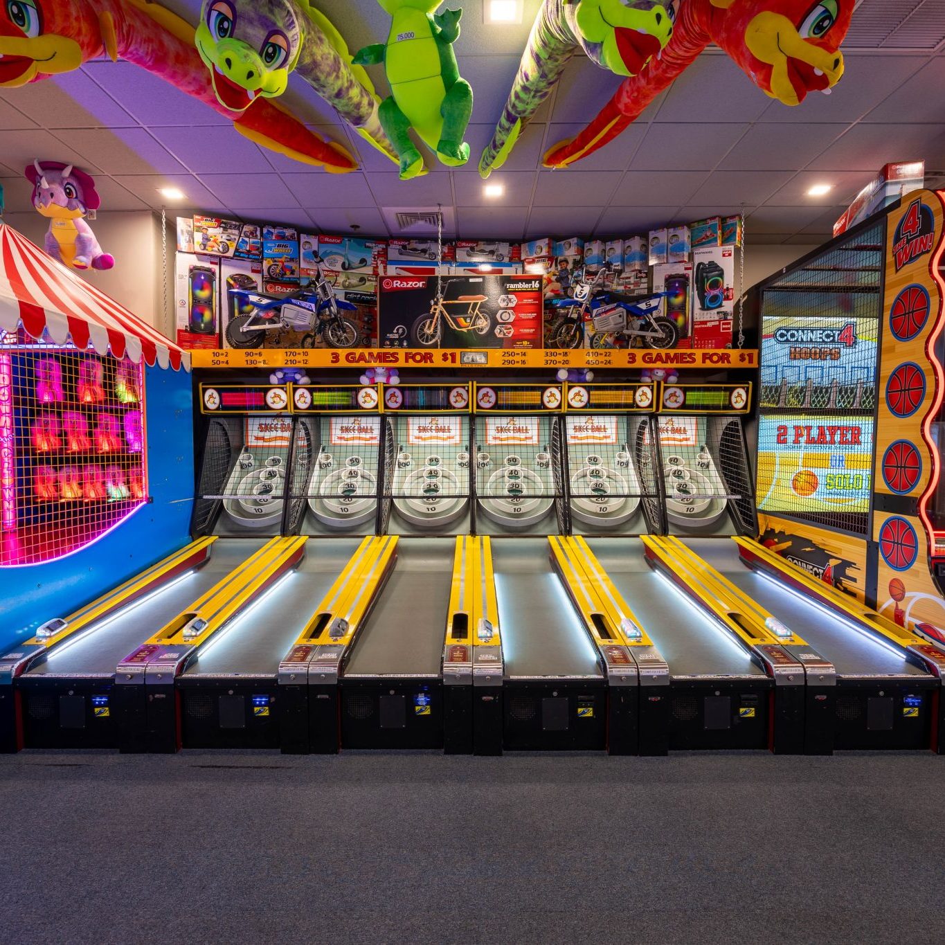 Indoor arcade featuring skee-ball lanes, basketball games, and colorful prize displays at Jenkinson’s Boardwalk.